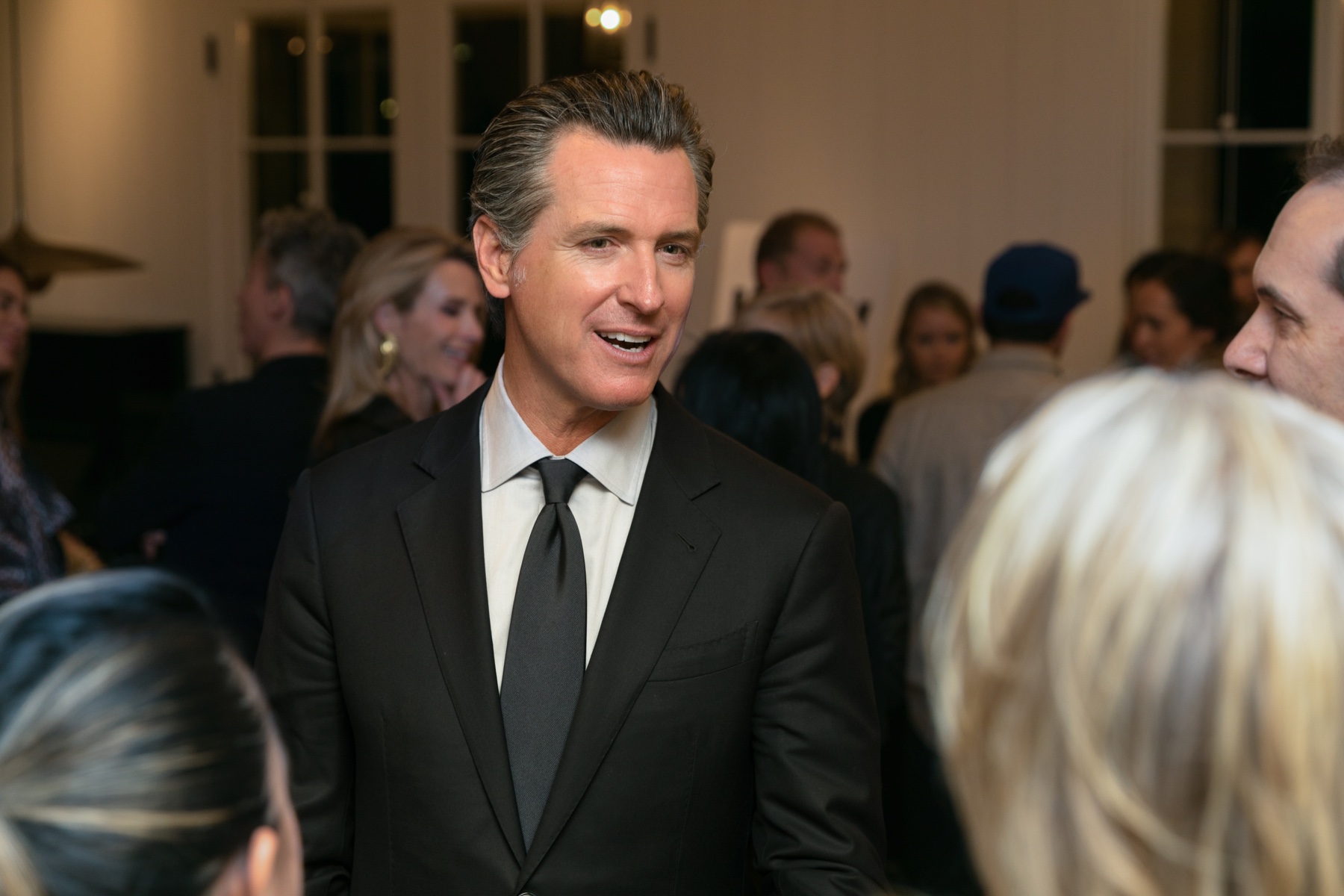 Gavin Newsom smiling and speaking with attendees at an event