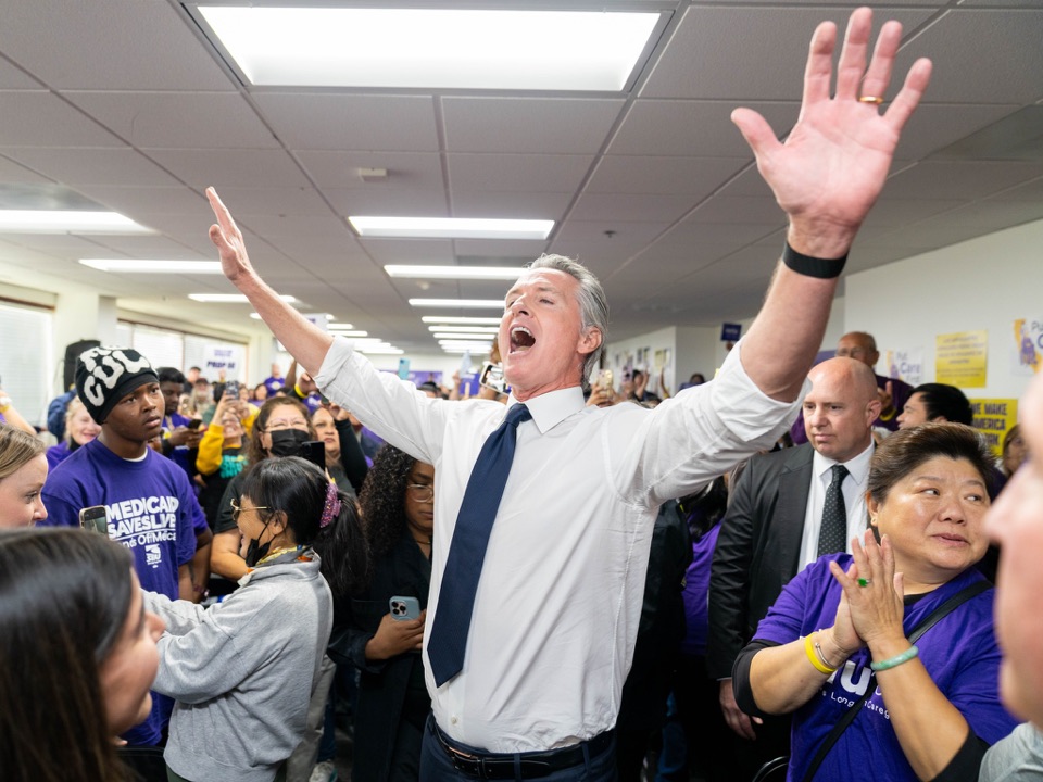 California Governor Gavin Newsom raising his hands among SEIU members