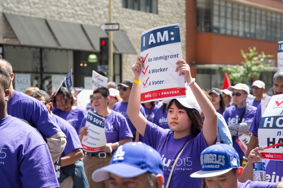 An SEIU 2015 member holding a sign reading I Am: An Immigrant, A Worker, A Voter